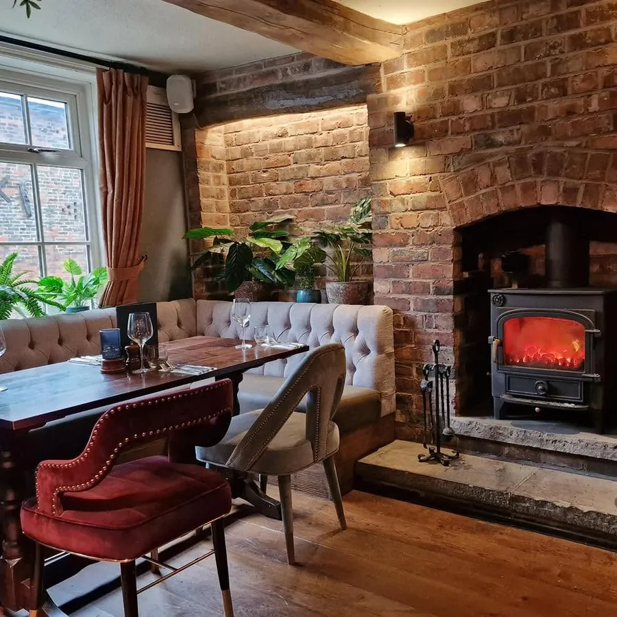 A booth table beside the log burner and exposed brick