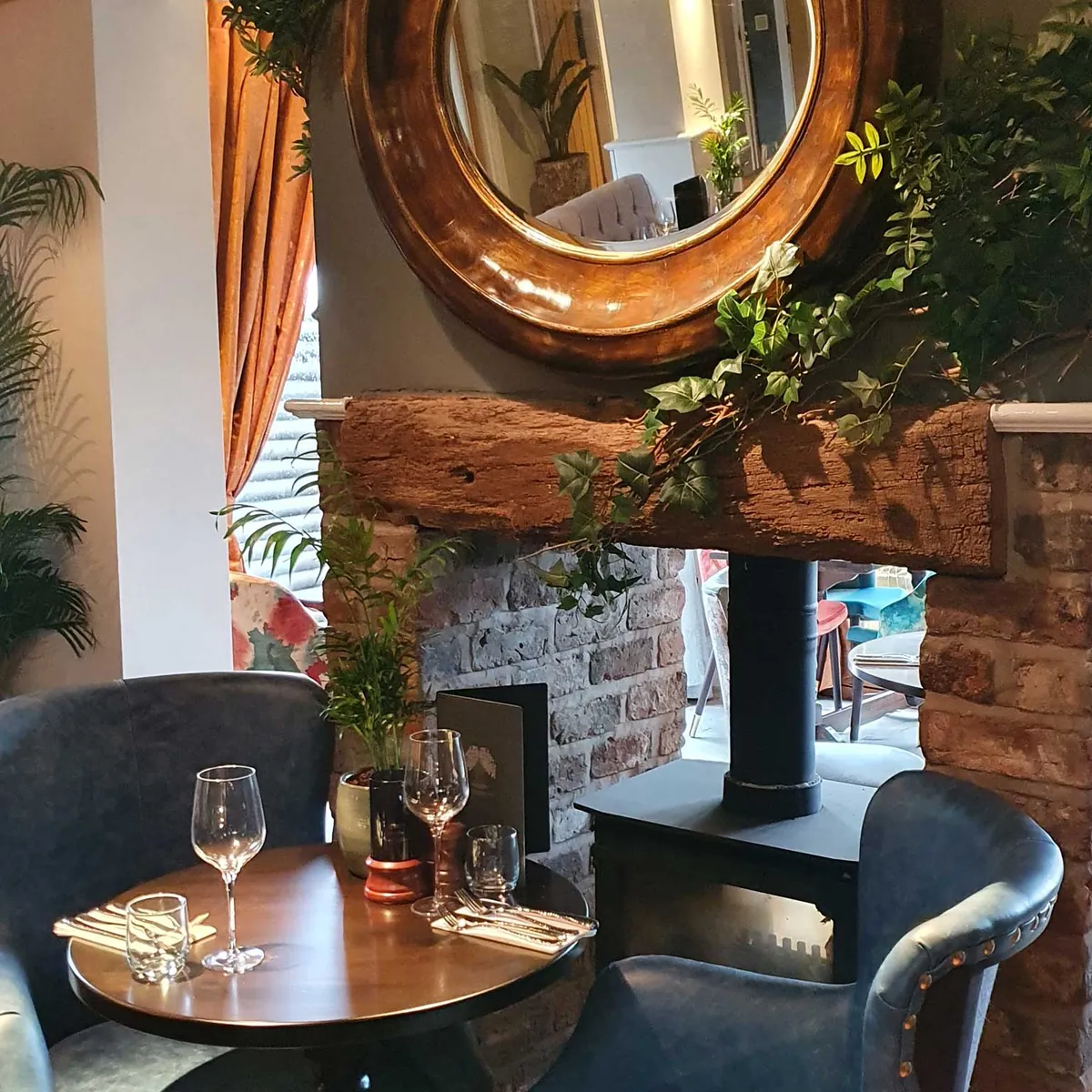 Tables by the log burner under a round gilt mirror