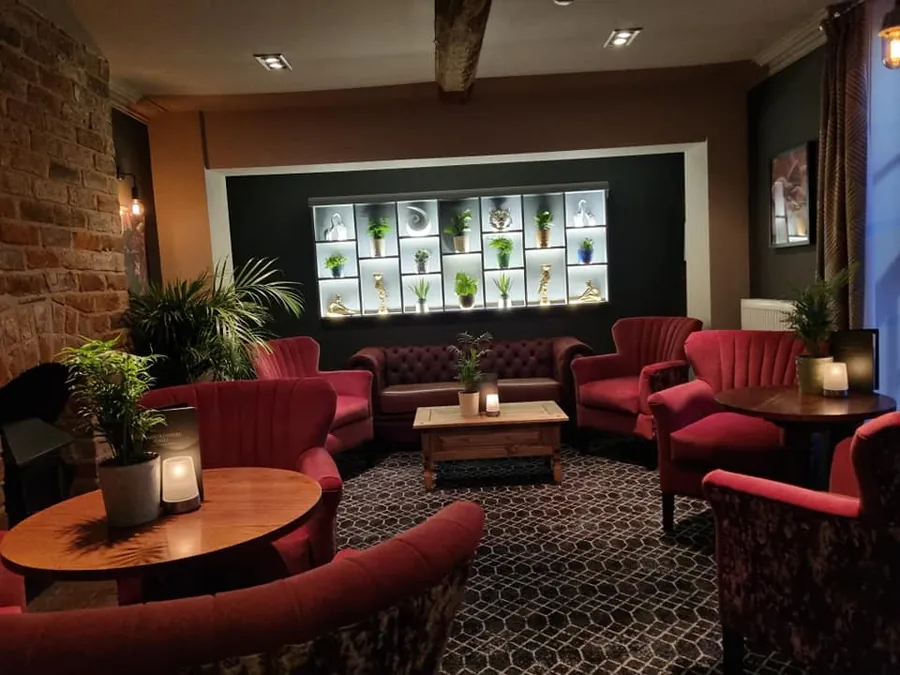 Red velvet armchairs and a lit display wall in the lounge