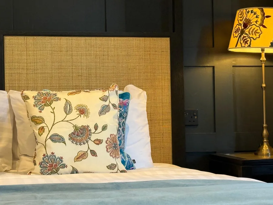 A bedroom with a woven headboard and floral cushions